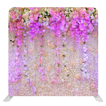 Decoratieve achtergrond met kunstbloemen in pastelkleuren en hangende bloemstengels, verlicht met roze en paarse tinten